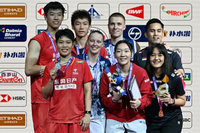 Gold medalists France's Thom Gicquel (3R) and Delphine Delrue (4L), silver medalists China's Feng Yan Zhe (L) and Huang Dong Ping (2L) pose on the podium alongside bronze medalists China's Jiang Zhen Bang (3L) and Wei Ya Xin (3R) and Indonesia's Nita Violina Marwah (R) and Amri Syahnawi during an awards ceremony at the end of the BWF World Championships mixed doubles final badminton match in the Indira Gandhi Indoor Stadium of New Delhi on August 23, 2026. (Photo by Sajjad HUSSAIN / AFP)