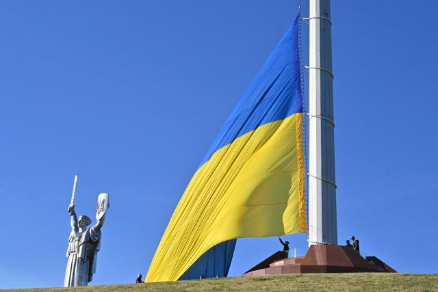 Ukrainian servicemen raise up the biggest national flag in the country on a flagpole in front of Motherland Monument during a ceremony marking the National Flag Day of Ukraine in Kyiv on August 23, 2026, amid Russian invaion of Ukraine. (Photo by Sergei SUPINSKY / AFP)