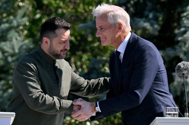 Ukrainian President Volodymyr Zelensky (L) and Norway's Prime Minister Jonas Gahr Store shake hands as they attend a ceremony marking the National Flag Day of Ukraine in Kyiv on August 23, 2026, amid Russian invaion of Ukraine. (Photo by Sergei SUPINSKY / AFP)