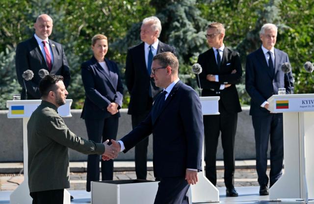 (L-R) Latvia's Prime Minister Andris Kulbergs, Denmark's Prime Minister Mette Frederiksen, Lithuania's President Gitana Nauseda, Finland's President Alexander Stubb  and Norway's Prime Minister Jonas Gahr Store  attend as Ukrainian President Volodymyr Zelensky (L -below) welcomes Estonia's Prime Minister Kristen Michal during ceremony marking the National Flag Day of Ukraine in Kyiv on August 23, 2026, amid Russian invasion of Ukraine. (Photo by Sergei SUPINSKY / AFP)