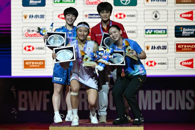 (L-R) Silver medalist Japan's Akane Yamaguchi, gold medalist South Korea’s An Se-young with bronze medalists China's Wang Zhi Yi and Thailand's Pornpawee Chochuwong celebrate on the podium during an awards ceremony at the end of the BWF World Championships women's singles final badminton match in the Indira Gandhi Indoor Stadium of New Delhi on August 23, 2026. (Photo by Sajjad HUSSAIN / AFP)