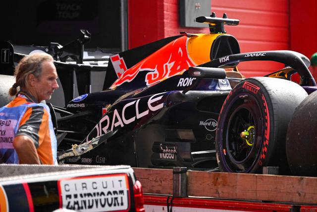 An employee stands next to the crashed car of Red Bull Racing's Dutch driver Max Verstappen during the Formula One Dutch Grand Prix at The Circuit Zandvoort, western Netherlands, on August 23, 2026. (Photo by JOHN THYS / AFP)