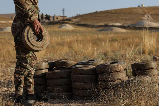 A Syrian army soldier piles up land mines as part of a demining operation by the Syrian Ministry of Defence's military engineering department in Qarah in the Damascus countryside on August 23, 2026. (Photo by Bakr ALkasem / AFP)