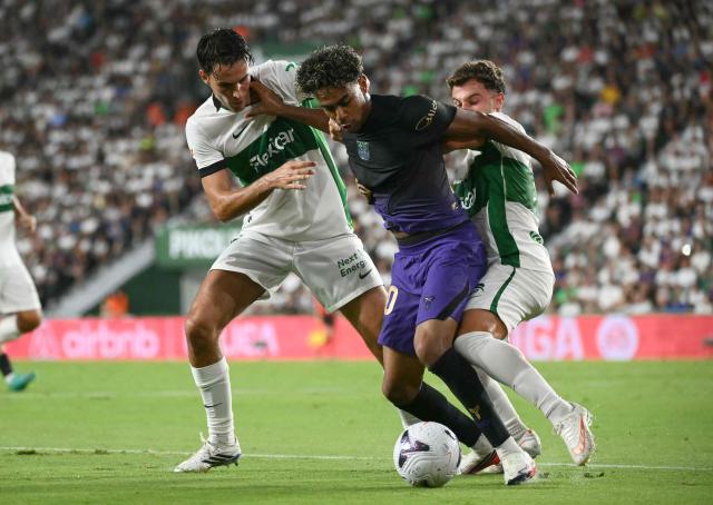 Barcelona's Spanish forward #10 Lamine Yamal fights for the ball with Elche's Spanish forward #11 German Valera and Elche's Argentine midfielder #05 Federico Redondo Solari (L) during the Spanish league football match between Elche CF and FC Barcelona at Martinez Valero Stadium in Elche on August 23, 2026. (Photo by JOSE JORDAN / AFP)