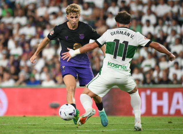 Barcelona's Spanish midfielder #07 Fermin Lopez fights for the ball with Elche's Spanish forward #11 German Valera during the Spanish league football match between Elche CF and FC Barcelona at Martinez Valero Stadium in Elche on August 23, 2026. (Photo by JOSE JORDAN / AFP)