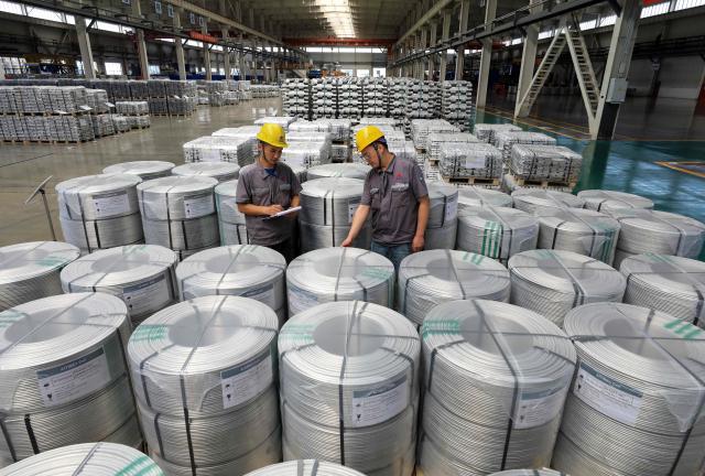 Workers supervise rolls of aluminum-titanium-boron, a core auxiliary material for aluminum-based products, at Anhui Dongbo Shengye New Materials Technology in Huaibei, eastern China's Anhui province on August 22, 2026. (Photo by CN-STR / AFP) / China OUT