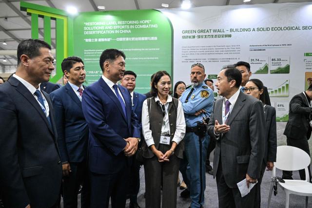 Mongolia's President Ukhnaagiin Khurelsukh (centre L) visits the Chinese booth in the delegation pavilion during the 17th Session of the Conference of the Parties (COP17) of the United Nations Convention to Combat Desertification (UNCCD) in Ulaanbaatar on August 24, 2026. (Photo by Hector RETAMAL / AFP)