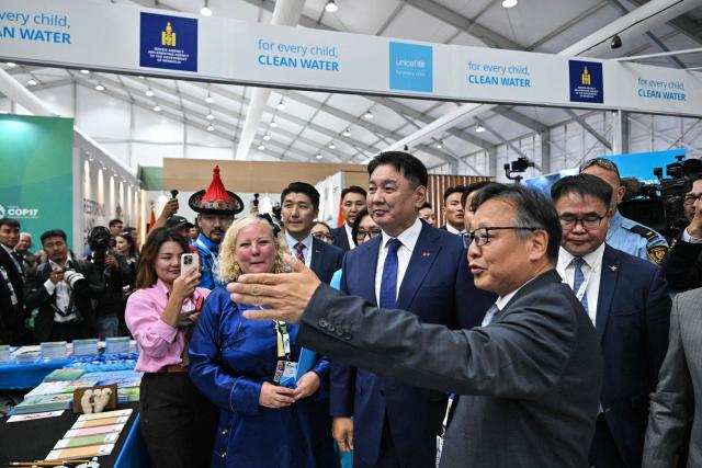 Mongolia's President Ukhnaagiin Khurelsukh (C) visits the delegation pavilion during the 17th Session of the Conference of the Parties (COP17) of the United Nations Convention to Combat Desertification (UNCCD) in Ulaanbaatar on August 24, 2026. (Photo by Hector RETAMAL / AFP)