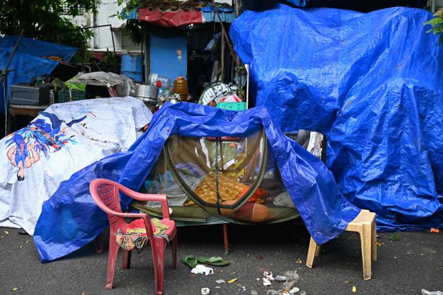 A woman sleeps inside a mosquito net outside her shack in Chennai on August 24, 2026. (Photo by R. Satish BABU / AFP)