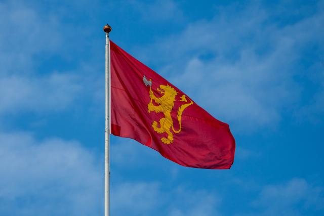 This picture taken on August 21, 2026 in Oslo shows the Royal Standard of Norway as it flutters atop the Palace. The Royal Standard depicts the Norwegian lion in gold bearing a silver axe on a red background and is hoisted whenever the King is in Norway or Norwegian territories. (Photo by Cornelius Poppe / NTB / AFP) / Norway OUT