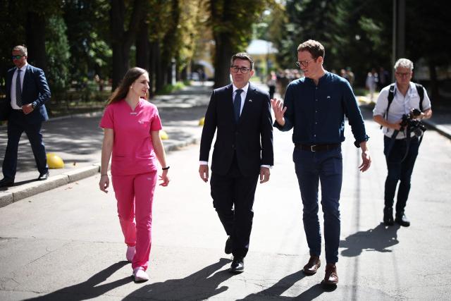 Britain's prime minister Andy Burnham (C) listens to explanations as he is welcomed by hospital staff members upon arrival at the Main Military Hospital, supported by the David Nott Foundation, a UK charity who have trained over 1,000 Ukrainian surgeons, anaesthetists and other healthcare workers, in Kyiv on August 24, 2026. Ukraine hosts a meeting of its key European backers on August 24 to press for critical air-defence supplies and more pressure on Moscow, with Russian attacks killing more civilians than at any time since the first months of the invasion. The leaders of Luxembourg, Moldova, Estonia and EU Council President Antonio Costa are also in Kyiv for the talks hosted on Ukraine's Independence Day and which come amid the war's latest escalation. (Photo by Henry Nicholls / POOL / AFP)