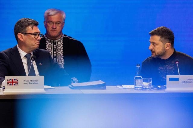 Britain's Prime Minister Andy Burnham (L) and Ukraine's President Volodymyr Zelensky (R) attend the Coalition of the Willing meeting, in Kyiv on August 24, 2026. The United Kingdom will keep providing defence aid to Ukraine despite Russia's threats, Prime Minister Andy Burnham said on August 24, 2026 on a visit to Kyiv where allies gathered to discuss support. Air defence supplies are due to be the main priority at the meeting of the Coalition of the Willing, jointly chaired by the leaders of France and Germany, who will participate remotely, and by Britain's Burnham. (Photo by Tetiana DZHAFAROVA / AFP)