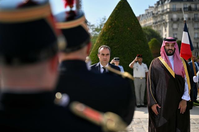 France's Prime Minister Sebastien Lecornu (L) stands at attention as he sings the French national anthem "La Marseillaise" during a welcoming ceremony for Crown Prince and Prime Minister of Saudi Arabia Mohammed bin Salman (R) as part of his two-day official visit to France, at the Hotel des Invalides in Paris on August 24, 2026. (Photo by Julie SEBADELHA / POOL / AFP)