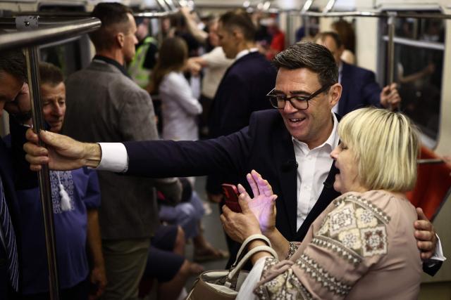 Britain's Prime Minister Andy Burnham (rear C) poses for a selfie picture with Kyiv's resident Natalia Bezrodeko as they stand in a metro carriage during the journey between the metro stations Zoloti Vorota and Lukanivska, in Kyiv, on August 24, 2026, as part of his first trip abroad since taking office. The United Kingdom will keep providing defence aid to Ukraine despite Russia's threats, Prime Minister Andy Burnham said on August 24, 2026 on a visit to Kyiv where allies gathered to discuss support. Air defence supplies are due to be the main priority at the meeting of the Coalition of the Willing, jointly chaired by the leaders of France and Germany, who will participate remotely, and by Britain's Burnham. (Photo by Henry NICHOLLS / POOL / AFP)