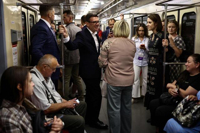 Britain's Prime Minister Andy Burnham (L) speaks with Kyiv's resident Natalia Bezrodeko, as they stand in a metro carriage during the journey between the metro stations Zoloti Vorota and Lukanivska, in Kyiv, on August 24, 2026, as part of his first trip abroad since taking office. The United Kingdom will keep providing defence aid to Ukraine despite Russia's threats, Prime Minister Andy Burnham said on August 24, 2026 on a visit to Kyiv where allies gathered to discuss support. Air defence supplies are due to be the main priority at the meeting of the Coalition of the Willing, jointly chaired by the leaders of France and Germany, who will participate remotely, and by Britain's Burnham. (Photo by Henry NICHOLLS / POOL / AFP)