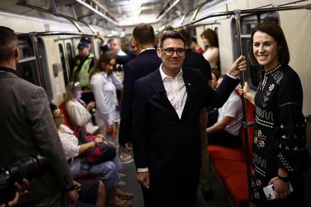 Britain's Prime Minister Andy Burnham (C) reacts as he stands in a metro carriage among passengers during the journey between the metro stations Zoloti Vorota and Lukanivska, in Kyiv, on August 24, 2026, as part of his first trip abroad since taking office. The United Kingdom will keep providing defence aid to Ukraine despite Russia's threats, Prime Minister Andy Burnham said on August 24, 2026 on a visit to Kyiv where allies gathered to discuss support. Air defence supplies are due to be the main priority at the meeting of the Coalition of the Willing, jointly chaired by the leaders of France and Germany, who will participate remotely, and by Britain's Burnham. (Photo by Henry NICHOLLS / POOL / AFP)