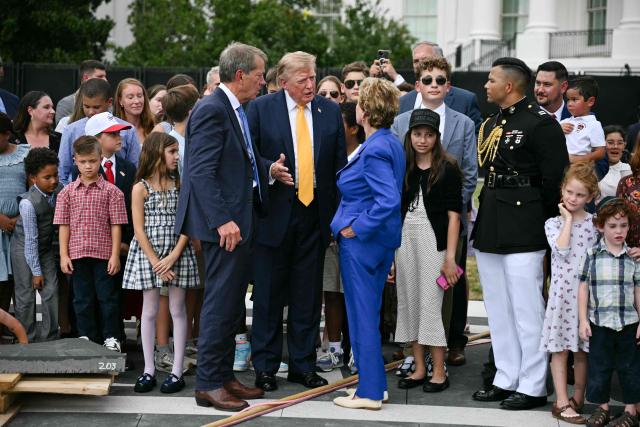 US President Donald Trump (C) speaks with Nebraska Governor Jim Pillen (L) and Secretary of Education Linda McMahon at the construction site of a helipad on the South Lawn of the White House in Washington, DC, on August 24, 2026. (Photo by Jim WATSON / AFP)