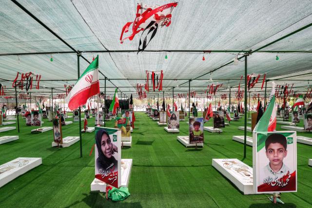 The graves of people and children killed during the strike on the Shajareh Tayebeh primary school are pictured at a cemetery in Minab in Irans Hormozgan province on August 10, 2026. Six months on, a team of AFP journalists obtained rare access to the school which has remained largely in ruins, its collapsed walls and twisted steel now surrounded by portraits of the children killed as Iranian flags flutter above the rubble. Iran says the attack on the school involved two separate US Tomahawk missiles but neither the United States nor Israel has officially claimed responsibility for the strike. (Photo by ATTA KENARE / AFP) / 