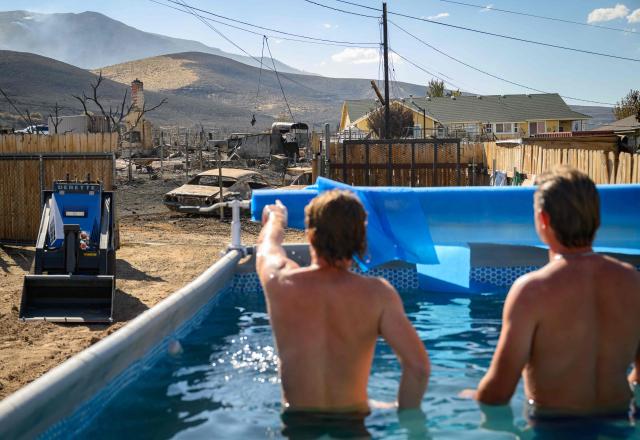 Residents watch the burned homes of their neighborhood while swimming in a backyard pool after they were destroyed by the Hawk Fire in Reno, Nevada on August 24, 2026. Tens of thousands of people looked set to spend another night away from home on August 24 as a wind-driven fire bore down on the western US city of Reno. Schools were shuttered as smoke swathed the city in Nevada, near the California border, home to around 280,000 people.
Around 24,000 were still under evacuation orders on Monday, officials said, down from over 40,000 at its peak. (Photo by Josh Edelson / AFP)