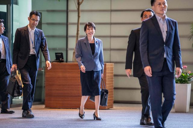 Japan's Prime Minister Sanae Takaichi (C) arrives at the Prime Minister's office in Tokyo on August 25, 2026. (Photo by Yuichi YAMAZAKI / AFP)