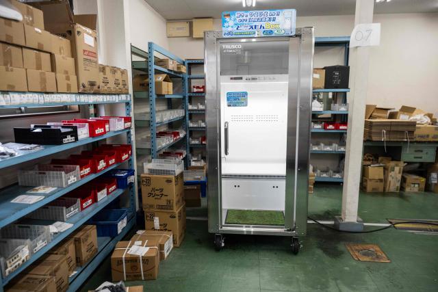 A cooling box for workers also known as a "human fridge is seen at the Konoe company warehouse, a specialist wholesaler of screws and surveying equipment, in Higashiosaka, Osaka Prefecture on August 21, 2026. The phonebooth-sized machine "Do Hiemon Box", where jets of ice-cold air ensure a temperature of 5C (41F), only launched this year but has proved popular in a country seemingly getting inexorably warmer. (Photo by ANDREW CABALLERO-REYNOLDS / AFP) / To go with AFP story Japan-climate-lifestyle-work, REPORTAGE by Hiroshi HIYAMA