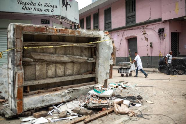 A street vendor walks past the rubble of a collapsed building 14 days after the 7.4-magnitude earthquake in Pereira, Colombia on August 24, 2026. The powerful earthquake that killed hundreds of people in western Colombia on August 10, 2026, caused $9.57 billion in economic losses, President Abelardo de la Espriella said on August 18, issuing a preliminary estimate. The death toll stands at 289, with a further 4,187 injured and 143 missing. (Photo by ESTEBAN VEGA LA-ROTTA / AFP)