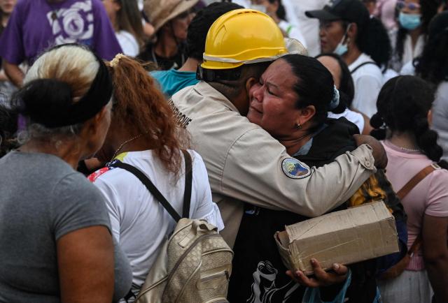 People hug during a mass with residents and relatives of the earthquake victims from the state-run OPP housing blocks two months after the 7.2 and 7.5-magnitude earthquakes in La Guaira, Venezuela on August 24, 2026. The magnitude 7.2 and 7.5 tremors on June 24, 2026, devastated the coastal state of La Guaira, where at least 190 buildings fell apart. Venezuela's interim government reported 6,509 deaths on August 24, 2026, exactly two months after the twin earthquakes. (Photo by Maryorin Mendez / AFP)