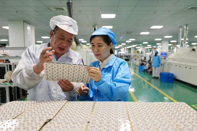Workers produce printed circuit boards at the production workshop of Jiangxi Keliang Lighting in Ruichang, in eastern China's Jiangxi province on August 24, 2026. (Photo by CN-STR / AFP) / China OUT