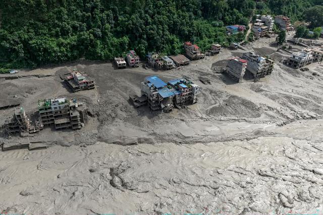 TOPSHOT - Houses lie partially submerged in muddy water along a riverside after flash floods at Trishuli Bazar in Nepal's Nuwakot district on August 26, 2026. A massive flood swept through Nepal's northern Rasuwa district on August 26, damaging roads and power infrastructure as authorities scrambled to assess the scale of the destruction. (Photo by Prabin RANABHAT / AFP)