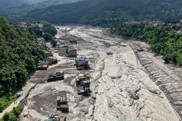 TOPSHOT - Houses lie partially submerged in muddy water along a riverside after flash floods at Trishuli Bazar in Nepal's Nuwakot district on August 26, 2026. A massive flood swept through Nepal's northern Rasuwa district on August 26, damaging roads and power infrastructure as authorities scrambled to assess the scale of the destruction. (Photo by Prabin RANABHAT / AFP)