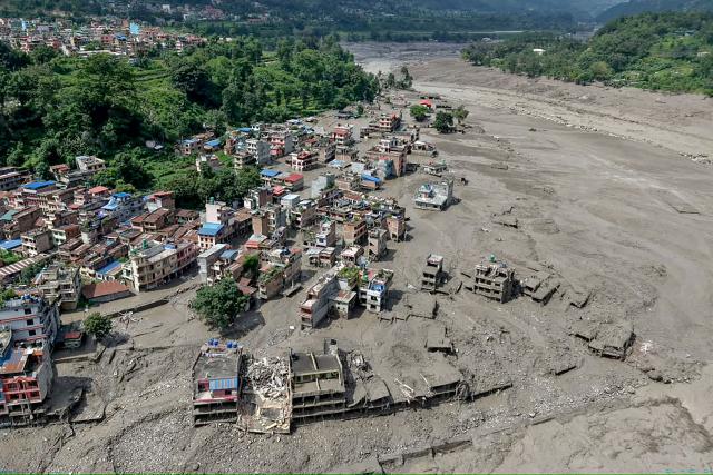 TOPSHOT - Houses lie partially submerged in muddy water along a riverside after flash floods at Trishuli Bazar in Nepal's Nuwakot district on August 26, 2026. A massive flood swept through Nepal's northern Rasuwa district on August 26, damaging roads and power infrastructure as authorities scrambled to assess the scale of the destruction. (Photo by Prabin RANABHAT / AFP)