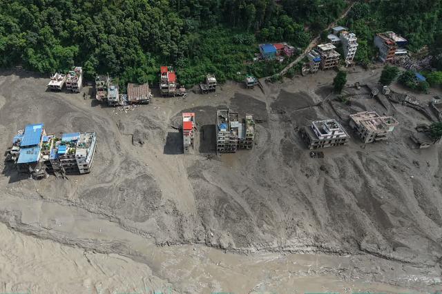 Houses lie partially submerged in muddy water along a riverside after flash floods at Trishuli Bazar in Nepal's Nuwakot district on August 26, 2026. A massive flood swept through Nepal's northern Rasuwa district on August 26, damaging roads and power infrastructure as authorities scrambled to assess the scale of the destruction. (Photo by Prabin RANABHAT / AFP)
