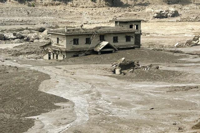 A house lies partially submerged in muddy water after flash floods at Trishuli Bazar in Nepal's Nuwakot district on August 26, 2026. A massive flood swept through Nepal's northern Rasuwa district on August 26, damaging roads and power infrastructure as authorities scrambled to assess the scale of the destruction. (Photo by Prakash MATHEMA / AFP)