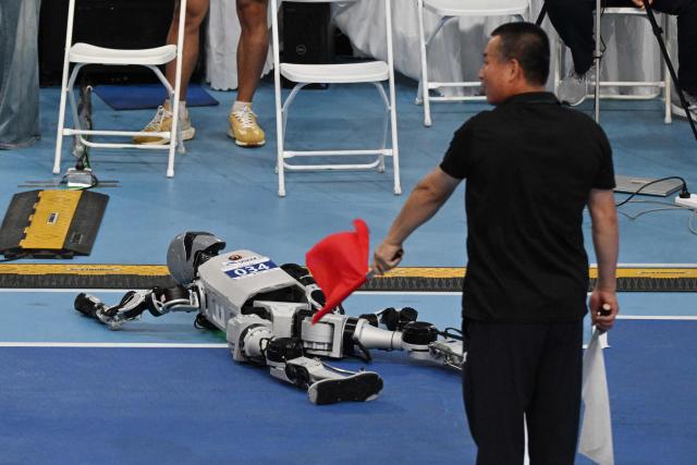 A humanoid robot is disqualified after falling during the long jump competition at the 2nd World Humanoid Robot Games at the National Speed Skating Oval in Beijing on August 26, 2026. (Photo by GREG BAKER / AFP)