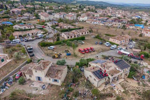 This photograph shows an aerial view of firefighters on roofs of houses destroyed after a tornado in Pomas, southwestern France, on August 26, 2025. Amid the rubble, firefighters, residents, and volunteers were hard at work on Augfust 26, 2026, after a tornado of rare intensity swept through, clearing, securing, and protecting more than 300 damaged houses, 102 of which were destroyed, in the village of Pomas in the Aude département. (Photo by Idriss Bigou-Gilles / AFP)