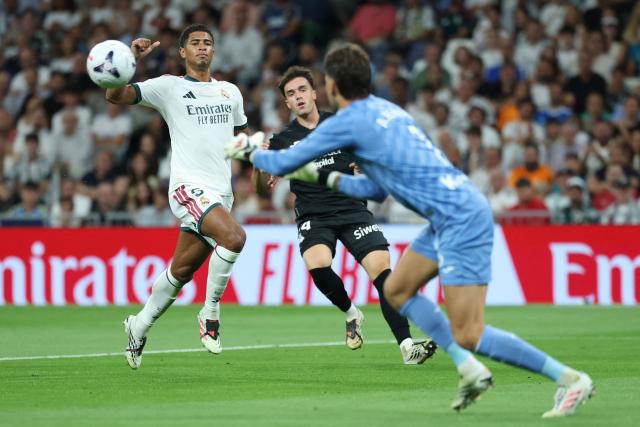 Real Madrid's English midfielder #05 Jude Bellingham (L) fails to score past Real Sociedad's Spanish goalkeeper #01 Alex Remiro during the Spanish league football match between Real Madrid CF and Real Sociedad  at Santiago Bernabeu Stadium in Madrid on August 26, 2026. (Photo by Thomas COEX / AFP)