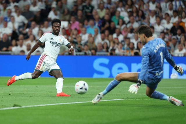 Real Madrid's Brazilian forward #07 Vinicius Junior (L) shoots challenged by Real Sociedad's Spanish goalkeeper #01 Alex Remiro during the Spanish league football match between Real Madrid CF and Real Sociedad  at Santiago Bernabeu Stadium in Madrid on August 26, 2026. (Photo by Thomas COEX / AFP)