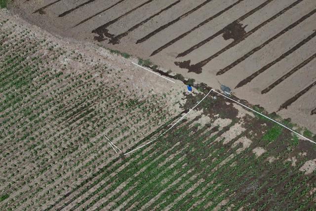 Aerial view of a farmer installing irrigation pipes to water his crops amid a lack of rainfall in Tecoluca, San Vicente department, El Salvador, on August 26, 2026. Farmers are relying on artificial irrigation to keep crops alive as the drought, associated with the El Nino phenomenon, reduces water availability and causes economic losses. El Salvador declared a red alert for meteorological and agricultural drought nationwide on August 25, 2026. (Photo by Marvin RECINOS / AFP)