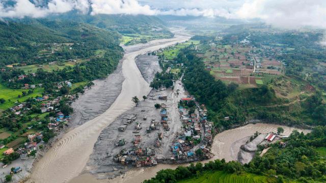 An aerial view shows houses lying deluged in sludge after flash floods at Devighat, Bidur Municipality, along the confluence of the Trishuli and Tadi rivers in Nepal's Nuwakot district on August 27, 2026. Nepal's disaster agency said that 823 people remained out of contact on August 27, more than 24 hours after a deadly flood tore through the border region with Tibet. (Photo by Prabin RANABHAT / AFP)