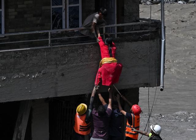 Rescue workers rescue stranded residents from a house buried in sludge after flash floods at Trishuli in Nepal's Nuwakot district on August 27, 2026. Rescue teams rushed on August 27 to find more than 1,300 people missing on the Nepal-Tibet border in flash floods and landslides that killed at least 165 and swept away entire villages. (Photo by Arun SANKAR / AFP)