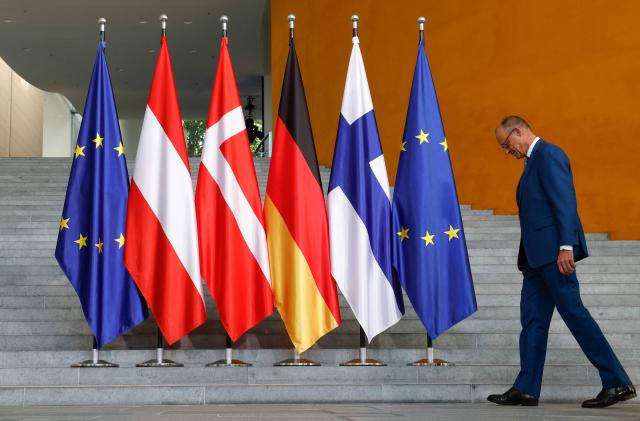 German Chancellor Friedrich Merz makes his way to pose for a group photo prior to a meeting at the Chancellery in Berlin, on August 27, 2026. (Photo by Odd ANDERSEN / AFP)
