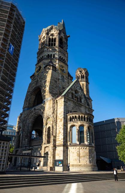 Outside view of the Kaiser Wilhelm Memorial Church (Kaiser-Wilhelm-Gedächtniskirche) that was not rebuilt as a reminder of World War II, with its modern belfry (L) in a scaffolding, in Berlin on August 27, 2026. The Kaiser Wilhelm Memorial Church in Berlin is to undergo renovation over the next three years at a cost of around 40 million euros. In the historic part of the church, the mosaics will be secured, the exhibition renewed, and the ruined tower made accessible to visitors, as Arne Herz, chairman of the Kaiser Wilhelm Memorial Church Foundation, announced. In the adjacent buildings from the 1960s, the concrete honeycomb structures and the blue glass windows, among other things, will be refurbished. (Photo by Odd ANDERSEN / AFP)