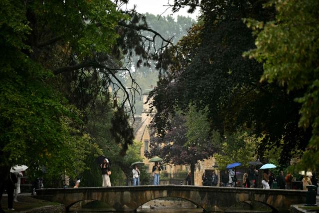 Visitors stand on a bridge in Bourton on the water, in a region known as the Cotswolds, north west of London on August 27, 2026. Prince Harry, his wife Meghan and their two children landed August 16 in Britain, UK media reported, after the shock news emerged last week they would be relocating from the United States. The Telegraph reported that the couple plan to stay for "an extended period", living in a home in the Cotswolds region, in central England, having enrolled their children at a school for the coming academic year. (Photo by JUSTIN TALLIS / AFP)