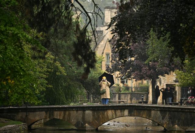 A person holds a smart phone whilst standing on a bridge in Bourton on the water, in a region known as the Cotswolds, north west of London on August 27, 2026. Prince Harry, his wife Meghan and their two children landed August 16 in Britain, UK media reported, after the shock news emerged last week they would be relocating from the United States. The Telegraph reported that the couple plan to stay for "an extended period", living in a home in the Cotswolds region, in central England, having enrolled their children at a school for the coming academic year. (Photo by JUSTIN TALLIS / AFP)