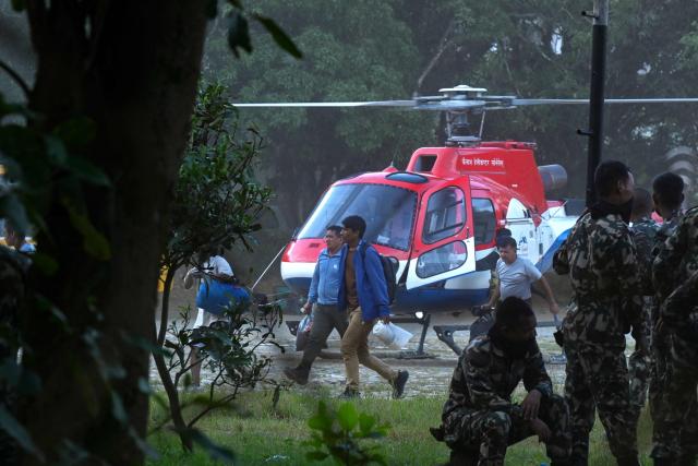 Rescued residents disembark a helicopter at an army camp following flash floods, in Battar Bazar town of Nepal's Nuwakot district on August 27, 2026. Rescue teams rushed on August 27 to find more than 1,300 people missing on the Nepal-Tibet border in flash floods and landslides that killed at least 165 and swept away entire villages. (Photo by Prakash MATHEMA / AFP)