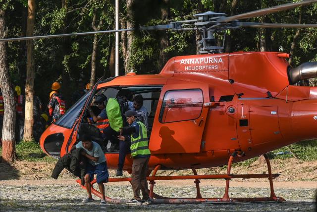 Rescued residents disembark a helicopter at an army camp following flash floods, in Battar Bazar town of Nepal's Nuwakot district on August 27, 2026. Rescue teams rushed on August 27 to find more than 1,300 people missing on the Nepal-Tibet border in flash floods and landslides that killed at least 165 and swept away entire villages. (Photo by Prakash MATHEMA / AFP)