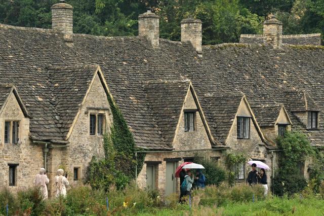 People walk past the Arlington Row Bibury, in a region known as the Cotswolds, north west of London on August 27, 2026. Prince Harry, his wife Meghan and their two children landed August 16 in Britain, UK media reported, after the shock news emerged last week they would be relocating from the United States. The Telegraph reported that the couple plan to stay for "an extended period", living in a home in the Cotswolds region, in central England, having enrolled their children at a school for the coming academic year. (Photo by JUSTIN TALLIS / AFP)