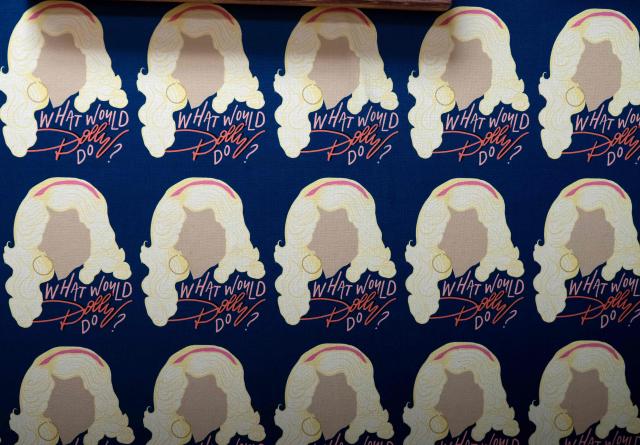 This photo taken on August 26, 2026,  shows images of Dolly Parton and the message "What would Dolly do?" on a wall inside the Southern Fried Hair Studio across the street from the Dolly Parton Statue in Parton's hometown of Sevierville, Tennessee. Parton, the country music star who rose from grinding poverty in Tennessee to become a rhinestone-studded cultural icon with hits like "Jolene" and "9 to 5," has died at 80, her family said on August 25, 2026. Parton was more than a singer -- she wrote 3,000 songs, acted in major Hollywood films and donated millions of dollars to charities in her home state and beyond. (Photo by A.M. Stewart / AFP)