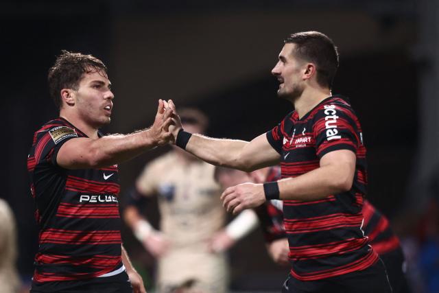(FILES) Toulouse’s French scrum-half Antoine Dupont (L) celebrates with Toulouse’s French full-back Thomas Ramos (R) at the end of the French Top14 rugby union match between Lyon Olympique Universitaire Rugby and Stade Toulousain Rugby (Toulouse) at the Gerland Stadium in Lyon, central-eastern France on December 20, 2025. The French Rugby Federation (FFR) announced on August 27, 2026, that Toulouse's fine for breaching the Top 14 salary cap has been reduced in a scandal that has played a part in the departure of full-back Thomas Ramos. In July, the record 25-time French champions were handed a 2.88 million euros (3.3 million dollars) penalty before it was decreased to 2.725 million euros following an appeal, for breaches in 2021-2022, 2022-2023 and 2024-2025. (Photo by Alex MARTIN / AFP)