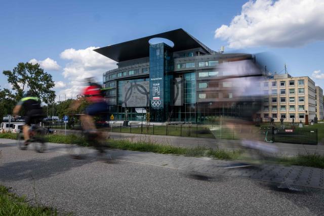A group of cyclists pass by the Olympic Centre building in Warsaw, where Poland's Olympic Committee has its headquarters, on August 27, 2026. Police on August 27, 2026 arrested the head of the Polish Olympic Committee on suspicion that he took bribes from a crypto trader in return for sponsorship deals, officials said. (Photo by Wojtek RADWANSKI / AFP)